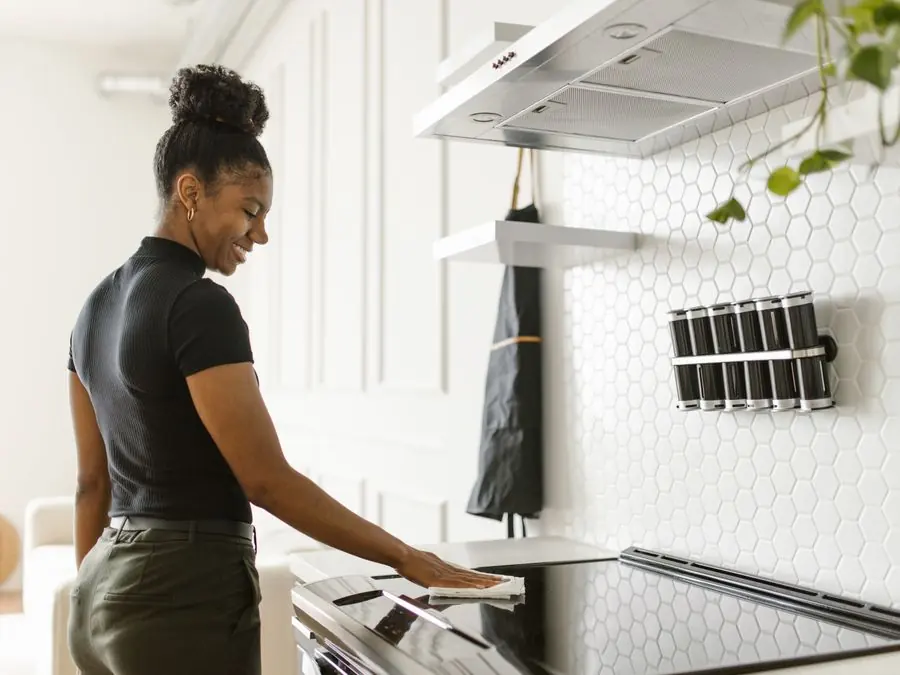 Une femme fait le ménage dans la cuisine d’un logement.