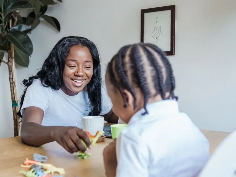 Une femme joue avec une petite fille assise à une table.